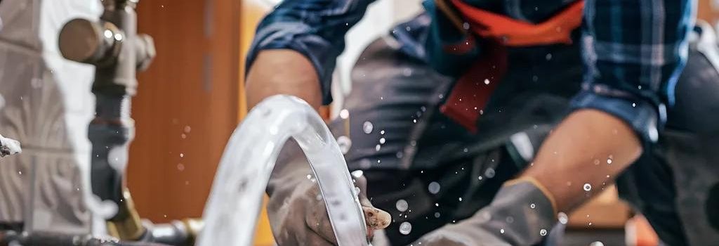 Professional plumber repairing a burst pipe in a residential home, showcasing emergency plumbing services